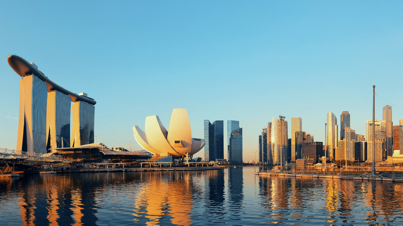 A panoramic view of Singapore’s Marina Bay skyline at sunrise, featuring Marina Bay Sands, the ArtScience Museum, and surrounding skyscrapers—symbolizing Singapore’s progress and prosperity, fitting for a feature on the SG60 Vouchers initiative.